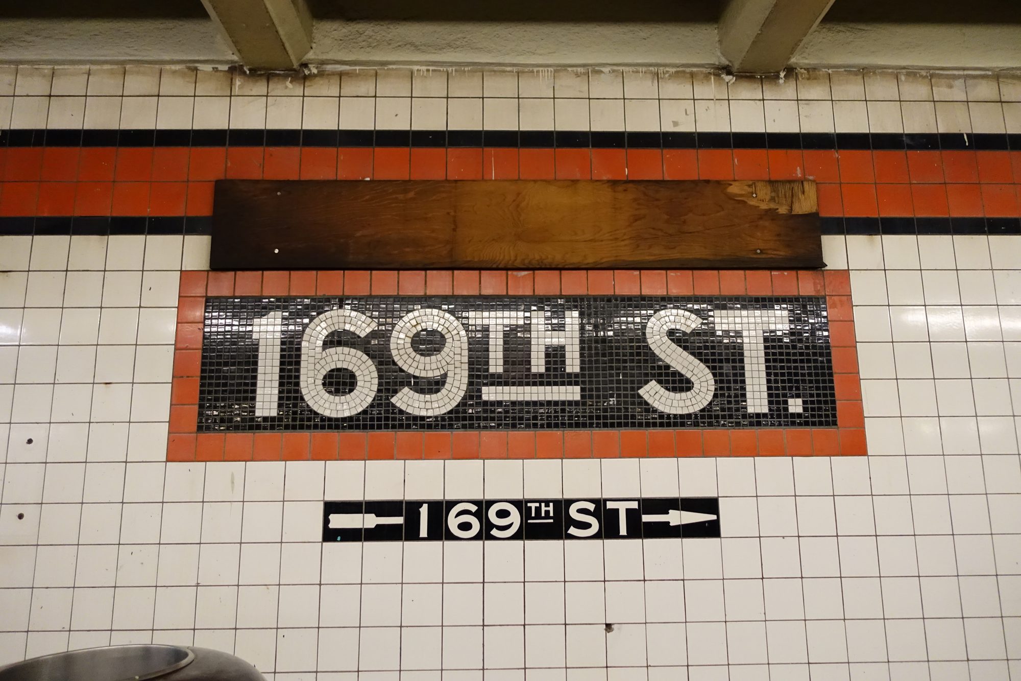 The Manhattan-bound platform of the 169th Street subway station under Hillside Avenue in Jamaica Hills, Queens, with light-green support beams.