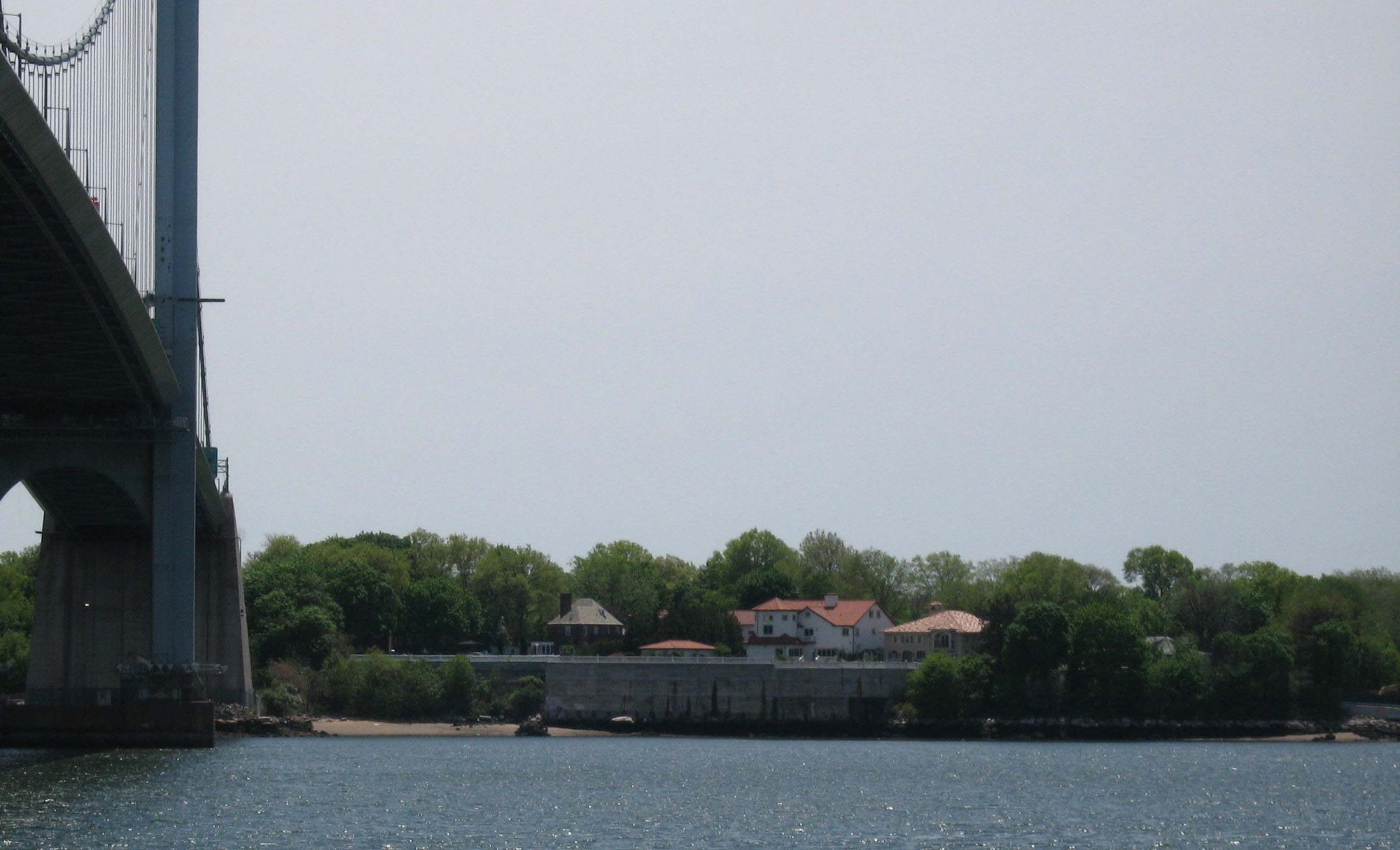 View of Malba across the water, with houses along the shoreline